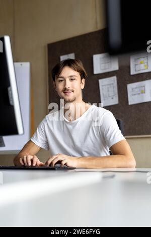 Giovane imprenditore seduto alla scrivania in ufficio Foto Stock