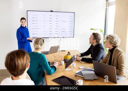 Giovane donna d'affari che fa una presentazione ai colleghi in ufficio Foto Stock