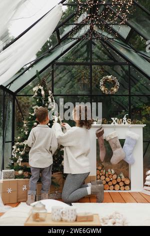 Madre e figlio decorare albero di Natale a casa Foto Stock