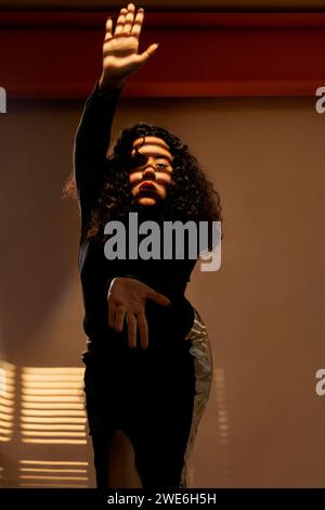 Giovane donna in piedi con le mani alzate davanti al muro Foto Stock