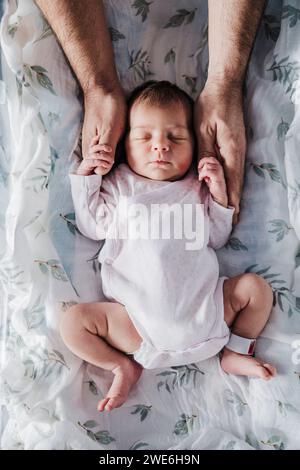 Mani di padre che tiene in mano una bambina addormentata Foto Stock