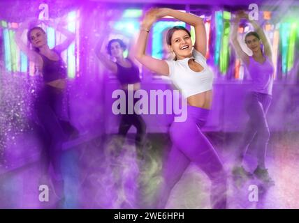 Immagine tonica con effetti visivi di una ragazza sorridente che esegue una danza energica in studio Foto Stock