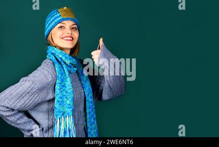 Donna felice con maglione, cappello e sciarpa lavorati a maglia. Moda femminile autunno-inverno. Bella ragazza con abiti caldi e alla moda con approvazione Foto Stock