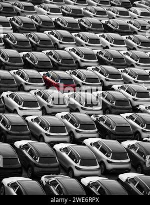 Zeebrugge Belgio Europa. 21.12.2024. Un'auto rossa tra le auto nuove parcheggiate sul molo per l'esportazione e l'importazione. il commercio di motori. Foto Stock