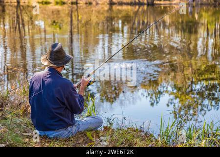 Uomo che pesca dalla riva di uno stagno privato vicino a Hattiesburg, Mississippi Foto Stock