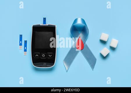 Nastro Awareness con cubetti di zucchero e glucometro su sfondo blu. Concetto di diabete Foto Stock