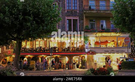 Scena notturna della strada principale medievale di Cochem sul fiume Mosella in Germania. Luci accese del ristorante a due livelli. Foto Stock