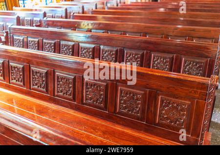 Panchine vuote in legno di una chiesa cristiana. Alterazione sfocata sullo sfondo. Messa a fuoco selettiva. Concetto di servizio religioso o chiese vuote. Righe Foto Stock