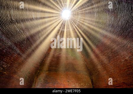 La luce del sole astratta attraverso il vecchio forno in mattoni abbandonato crea un aspetto misterioso. Forno per mattoni metodo manuale di fabbricazione dei mattoni nel XIX secolo Foto Stock