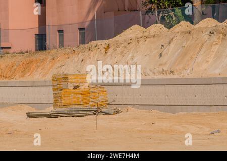 Forme di calcestruzzo e tubi per ponteggi in ferro impilati ordinatamente davanti a una parete in cemento presso il cantiere in Corea del Sud Foto Stock