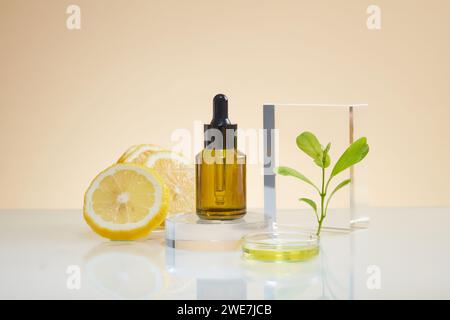 Una bottiglia di vetro con contagocce in piedi sul podio rotondo, alcune fette di limone, foglie verdi e petri di liquido visualizzati. Mockup di prodotto cosmetico sierico Foto Stock