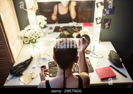 Visuale ad alto angolo con esecutori irriconoscibili che si truccano con lo specchio di cortesia nel backstage del teatro o del circo Foto Stock