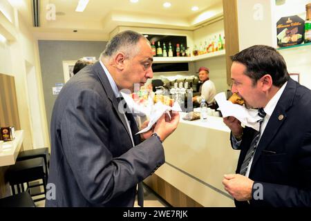 Uomini d'affari italiani che mangiano Arancini al Bar Touring di Palermo, Sicilia, Italia. Foto Stock