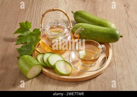 Un vassoio di legno a forma rotonda con un set da tè trasparente e un fresco melone verde invernale. Il melone invernale (Benincasa hispida) è un ottimo cooli Foto Stock