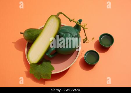 Melone invernale tagliato a metà su un piatto con teiera verde scuro. Due tazze ripiene di tè accanto. Il melone invernale (Benincasa hispida) ha molti bene Foto Stock