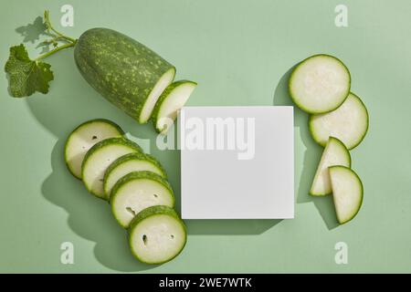 Podio quadrato di colore bianco visualizzato su sfondo pastello con fette di melone invernale. Il melone invernale (Benincasa hispida) può ridurre la minaccia di severa Foto Stock