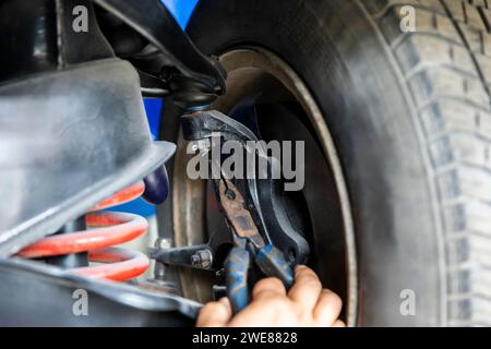 Meccanico che cerca un perno con pinze, affronta un'attività di manutenzione che coinvolge componenti complessi. Foto Stock