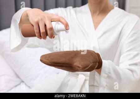 Autoabbronzante. Donna che applica il prodotto cosmetico sul guanto abbronzante in interni, primo piano Foto Stock