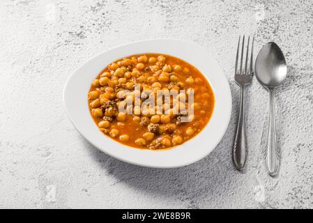 Stufato di ceci con carne macinata su un piatto di porcellana bianca su un tavolo di pietra Foto Stock