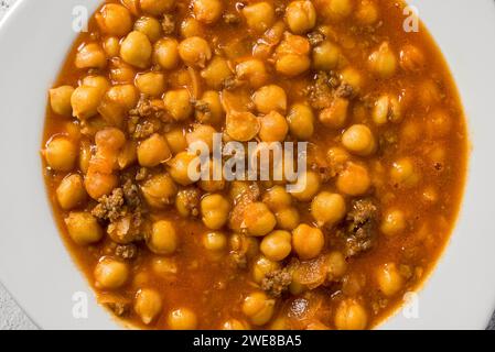 Stufato di ceci con carne macinata su un piatto di porcellana bianca su un tavolo di pietra Foto Stock