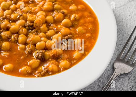 Stufato di ceci con carne macinata su un piatto di porcellana bianca su un tavolo di pietra Foto Stock