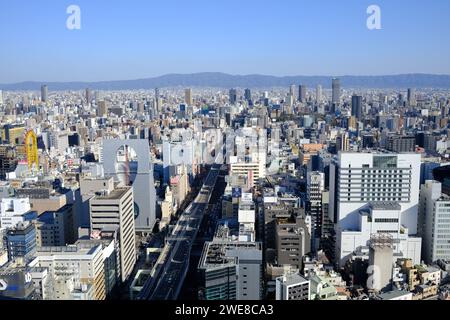Un'ampia vista aerea cattura la fitta struttura urbana di Osaka, in Giappone, con un cielo limpido in alto Foto Stock
