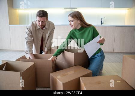 Famiglia coppia uomo donna che disimballano scatole con cose dopo essersi trasferito in un nuovo appartamento. Trasferimento. Foto Stock