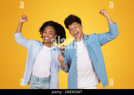 Due giovani persone gioiose con le braccia alzate in vittoria, condividendo un momento trionfale Foto Stock