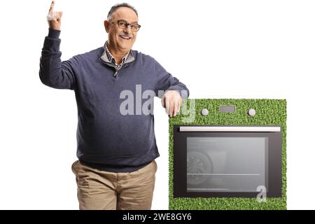 Uomo maturo sorridente con una stufa a risparmio energetico che punta verso l'alto isolato su sfondo bianco Foto Stock