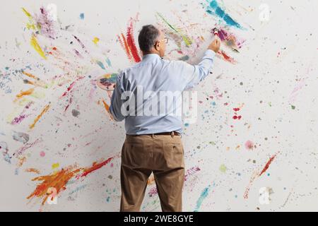 Immagine retrovisiva di un uomo maturo che dipinge con vernici aciliche su una parete Foto Stock