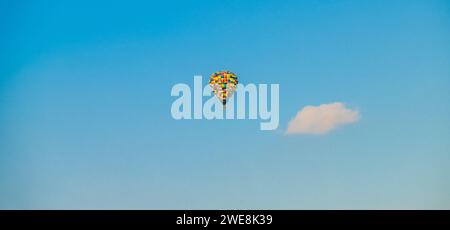 Scatto panoramico di una mongolfiera multicolore vista contro un cielo blu Foto Stock
