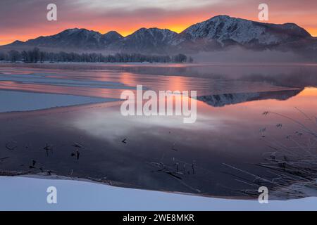 Rossore mattutino sul lago ghiacciato di fronte alle montagne, lago Kochelsee, alta Baviera, Baviera, Germania, Europa Foto Stock