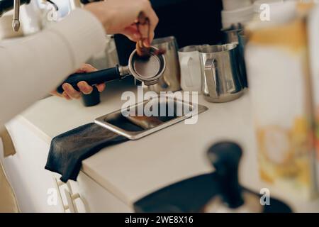 Il primo piano del barista professionista è la pulizia e l'asciugatura di un portafiltro dopo l'uso Foto Stock