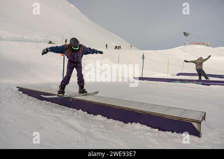 Trucchi per lo Snow Park. Snowboarder nel parco su una scatola. Jibbing invernale nello snwopark in Francia.. Foto Stock