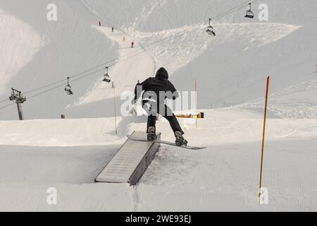 Trucchi per lo Snow Park. Snowboarder nel parco su una scatola. Jibbing invernale nello snwopark in Francia.. Foto Stock