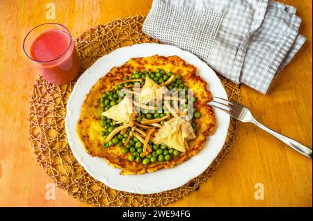 Omelette all'uovo con pisello bollito, funghi shimeji fritti e formaggio svizzero a forma di rosa su piatto bianco sul tavolo, bevanda, asciugamano, primo piano. Foto Stock