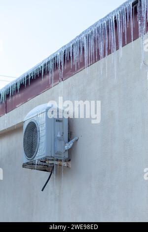 Il balsamo ricoperto di ghiaccio su una parete gialla. Funzionamento del climatizzatore in inverno a basse temperature. Immagine concetto di raffreddamento e freddo. Foto Stock