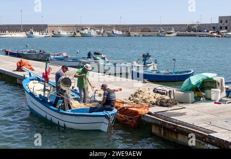 MOLFETTA, ITALIA, 10 LUGLIO 2022 - pescatori che preparano le reti per la pesca nel porto turistico di Molfetta, Puglia, Italia Foto Stock