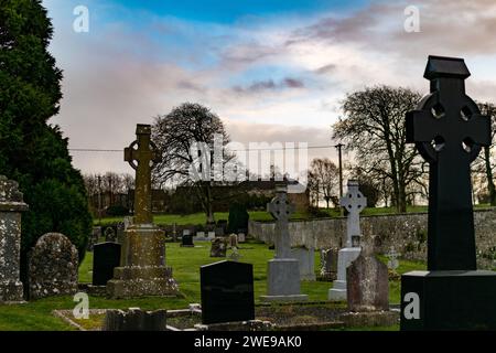 Sereno cimitero al crepuscolo con croci celtiche e lapidi contro un cielo spettacolare. Foto Stock