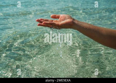 Mani con acqua pura. Primo piano della mano di una donna che tocca l'acqua del lago. La mano di una persona che si allunga per toccare una superficie d'acqua che si ripete, esplorando la Foto Stock