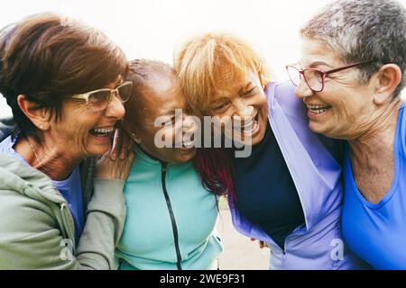 Donne anziane multirazziali che si divertono insieme dopo l'allenamento sportivo all'aperto - stile di vita sano e concetto di persone mature Foto Stock