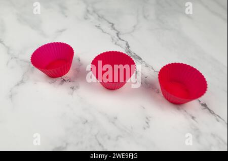 Vista dall'alto delle custodie per cupcake in silicone su sfondo in marmo bianco. Cottura di muffin e cupcake, stesa piatta, spazio per copiare. Foto Stock