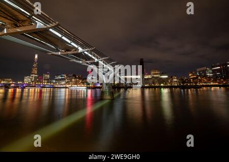 Londra. UK-01.20.2024. Ripresa a lunga esposizione del Millennium Bridge di notte con riflessi luminosi sul Tamigi. Foto Stock