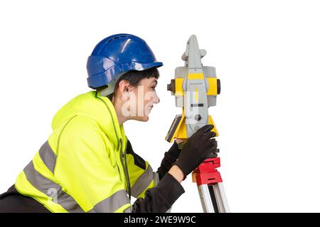 Donna con elmetto blu e indumenti protettivi gialli, topografia che lavora con moderni strumenti geodetici tachimetro per il controllo delle coordinate. Foto Stock