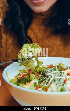primo piano di una donna irriconoscibile che mangia insalata con forchetta. vista frontale. Foto Stock