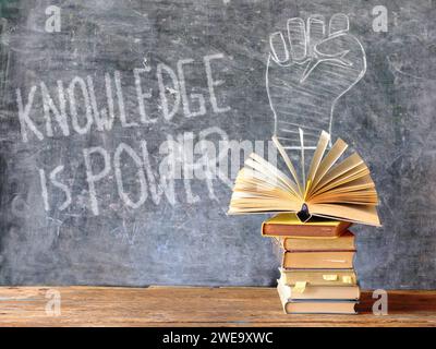 la conoscenza è potere, libri e lavagna con disegno di un simbolo di potere pugno, educazione, apprendimento, lettura, idea, concetto di ritorno a scuola. Foto Stock