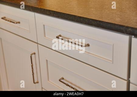 Eleganti armadi bianchi con manici in ottone e ripiano in granito, vista ravvicinata Foto Stock