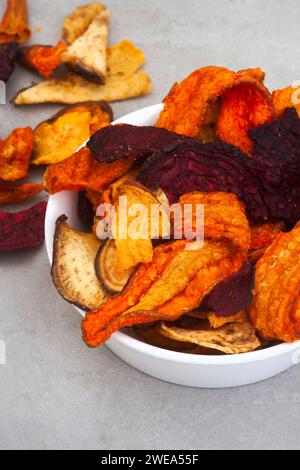 Patatine a base di verdure a radice. Carote, barbabietole e patate dolci. Su una superficie grigia a chiazze con spazio di copia Foto Stock