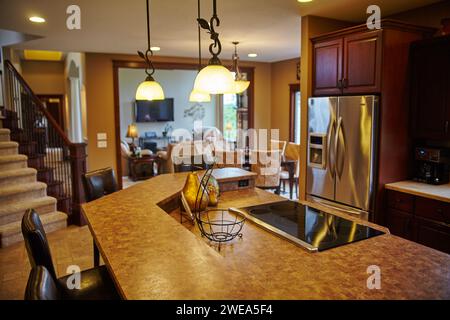 Cucina moderna a pianta aperta e zona soggiorno con calde tonalità di legno Foto Stock