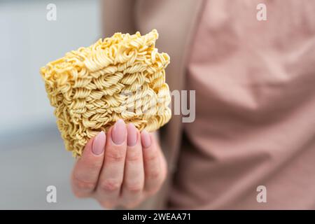 Mano che regge spaghetti gialli essiccati su sfondo bianco. Foto Stock